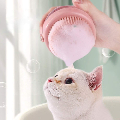 Pink silicone bath brush gently bathing a cat with rich foam using the built-in shampoo dispenser.
