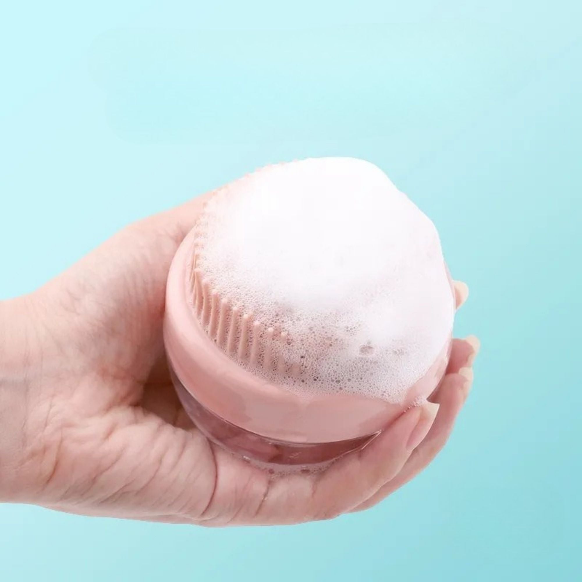 Pink silicone shampoo dispensing bath brush covered with rich foam.